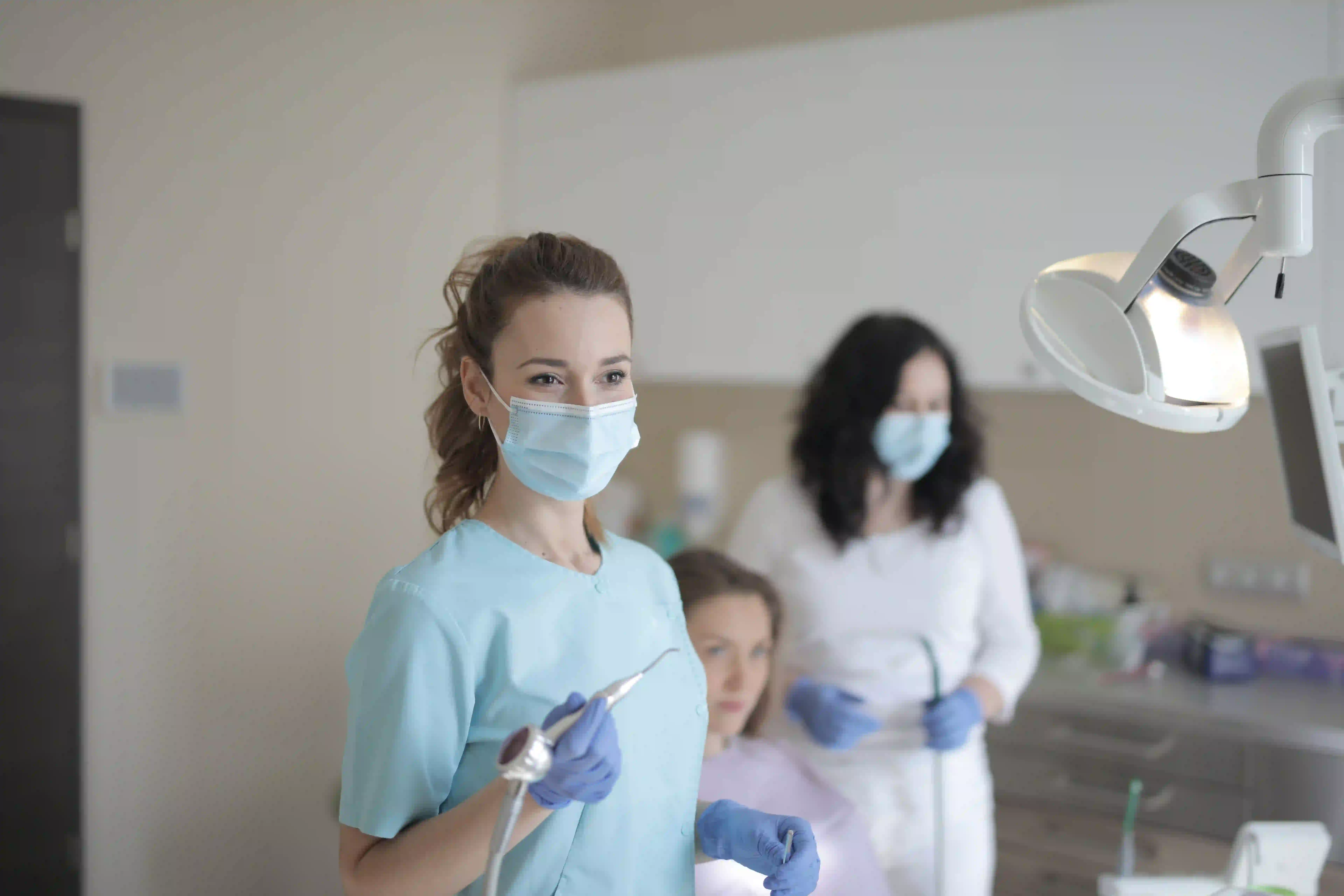 young-female-dentist-working-with-assistant-while-treating-3884095